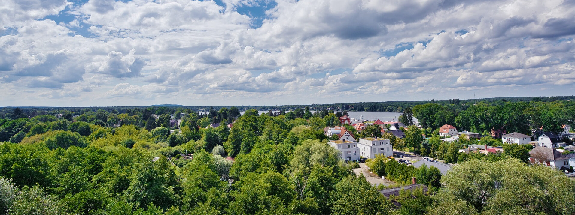 Grüne Landschaft mit Häusern und Wolken am Himmel.
